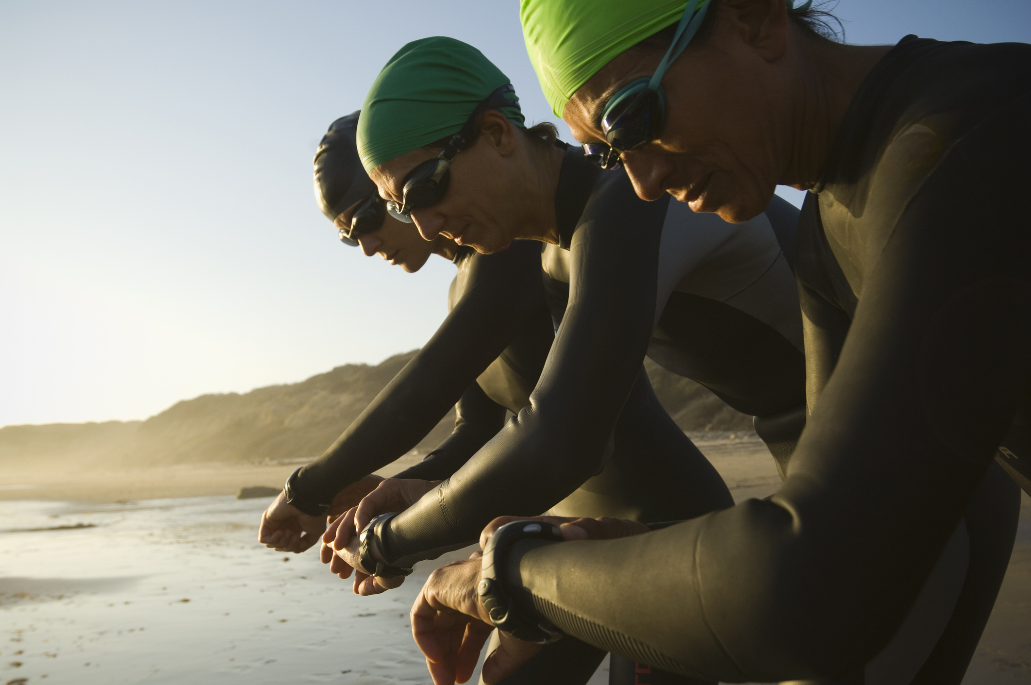 Multi-ethnic swimmers checking watches Multi-ethnic swimmers checking watches