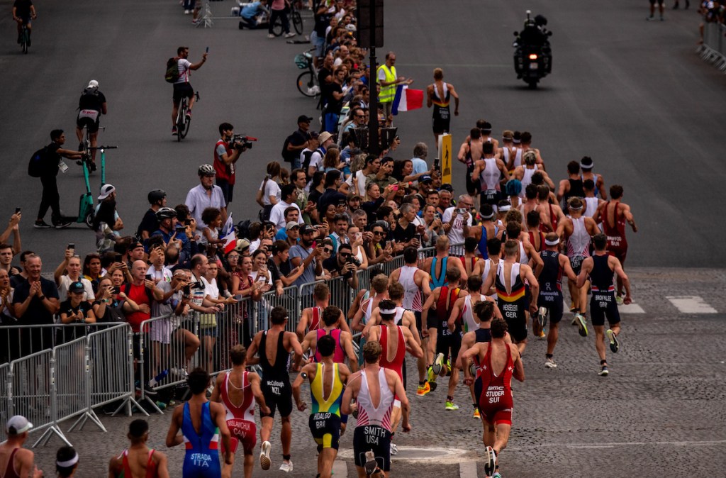 The pro men run past huge crowds along the cobbled streets of Paris at the Paris Olympics triathlon test event in 2023