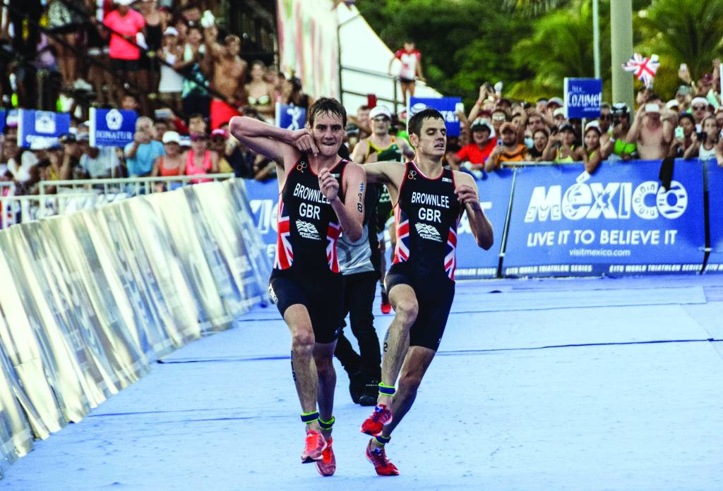 British athlete Alistair Brownlee (L) helps his brother Jonathan Brownlee (R) before crossing the line in second and third place during the ITU World Triathlon Championships 2016 in Cozumel, Quintana Roo, Mexico on September 18, 2016.