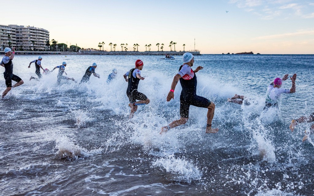 Male triathletes race into the sea at the start of French Riviera T100 2025