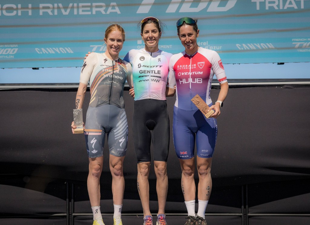 Three female triathletes standing on podium steps