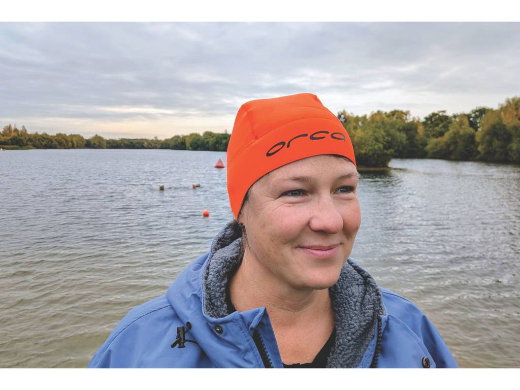 Woman wearing orange swim hat by water