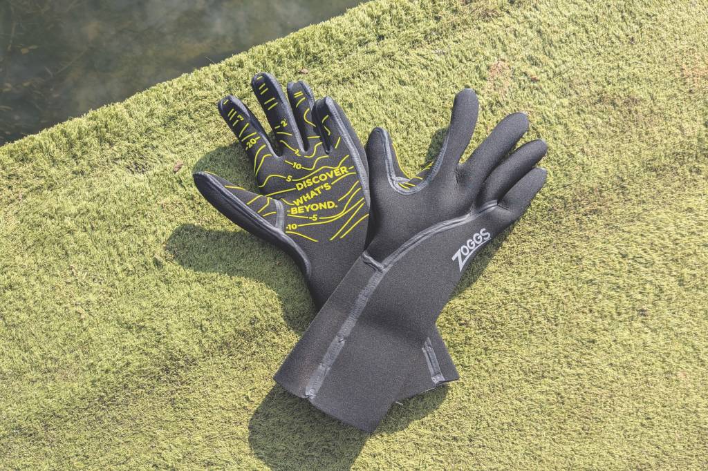 Black swimming gloves on astroturf by water