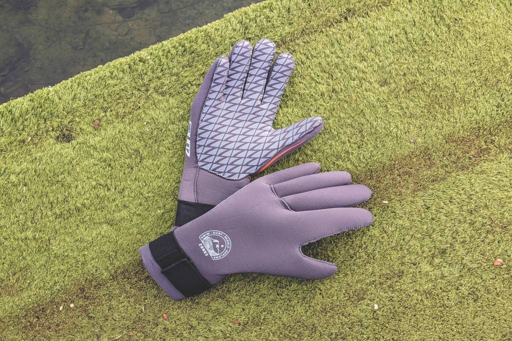 Grey swimming gloves on astroturf by water
