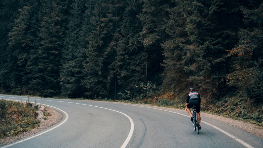 Man riding bicycle around winding forest road