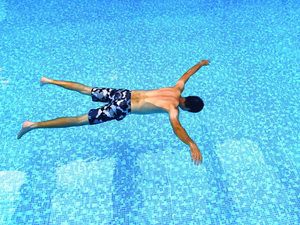 Male swimmer demonstrating X float technique in pool