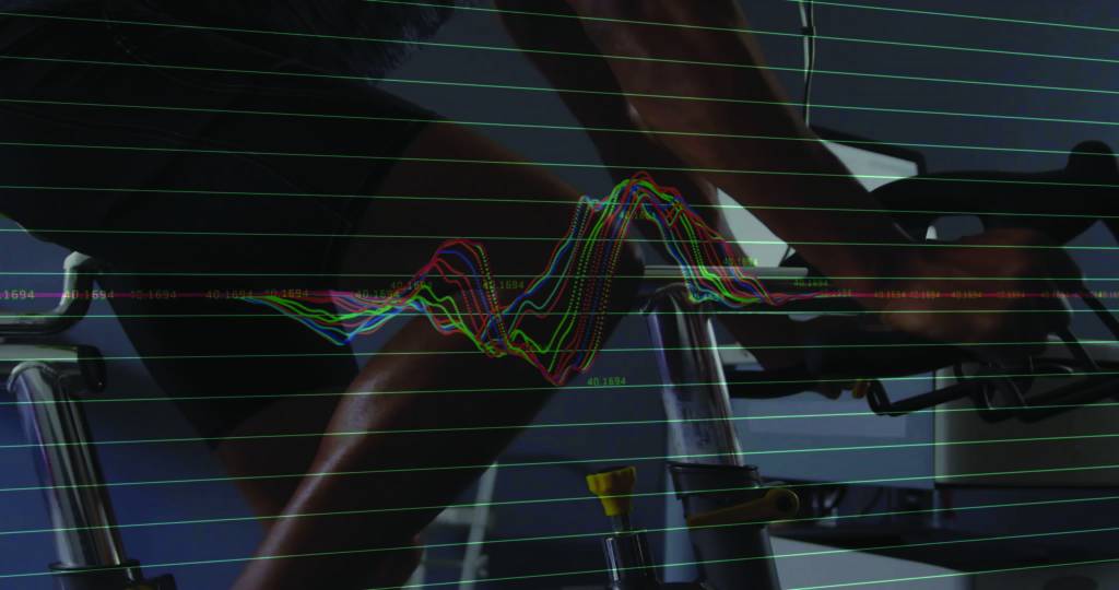 Pedaling man wearing fitted athletic gear on stationary bike in fitness lab, with waveform overlay. Health, technology, innovation, sports, performance, data, biomechanics