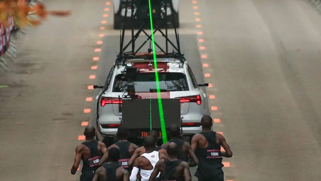 Male athletes run behind car