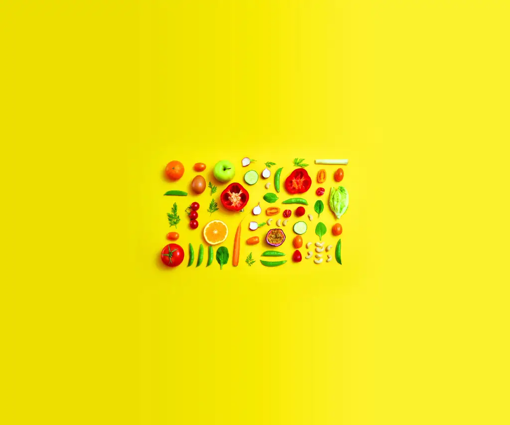 Colourful flat lay view sliced fruits and vegetables on yellow background.