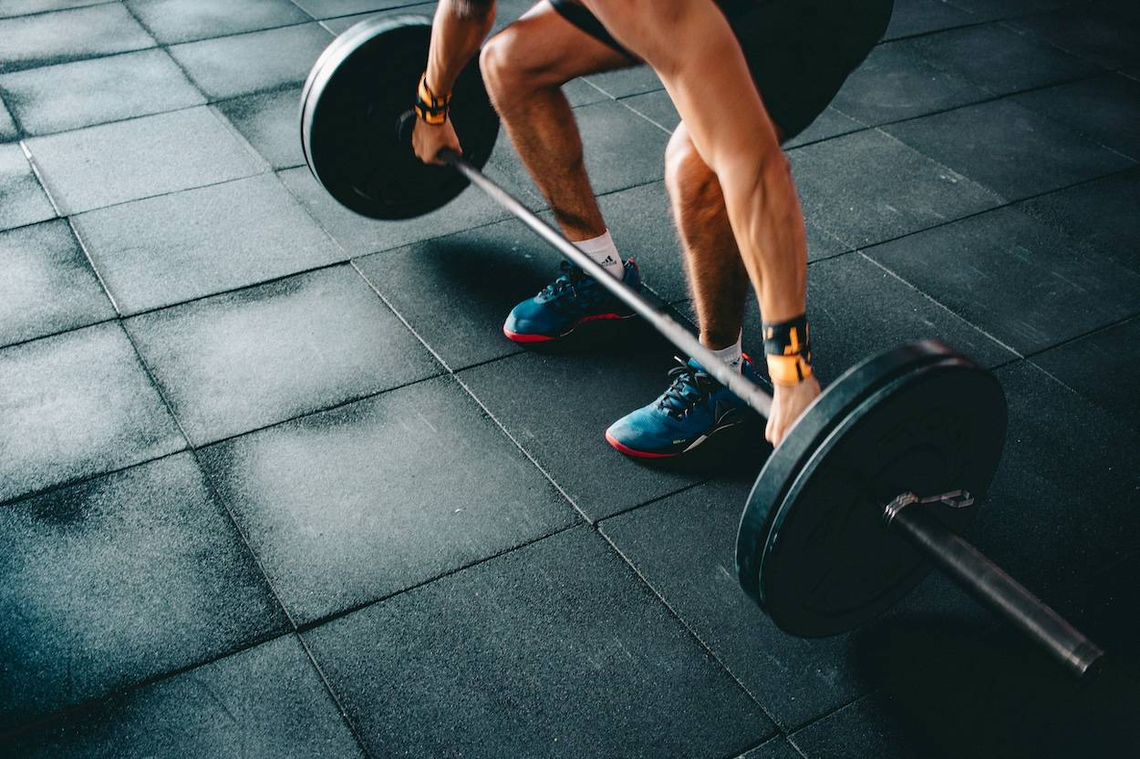 Close-up of a man's hands and feet as he lifts a barbell in the gym