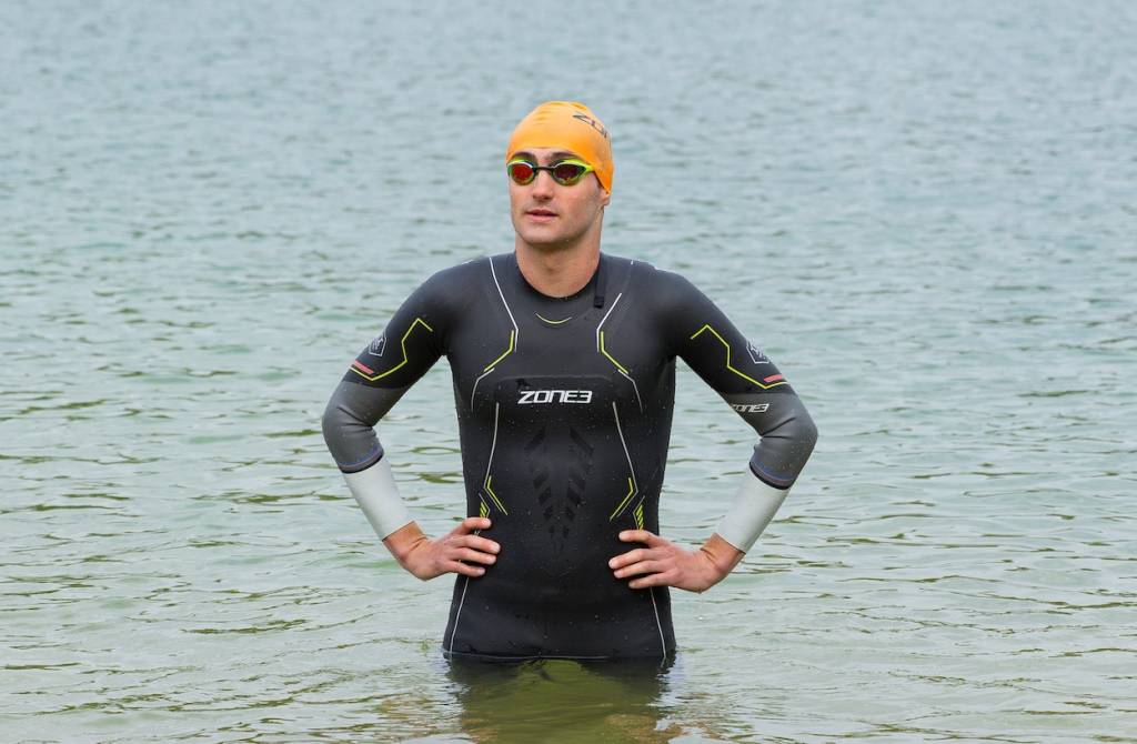 Triathlete Kieran Lindars standing in the water in a wetsuit