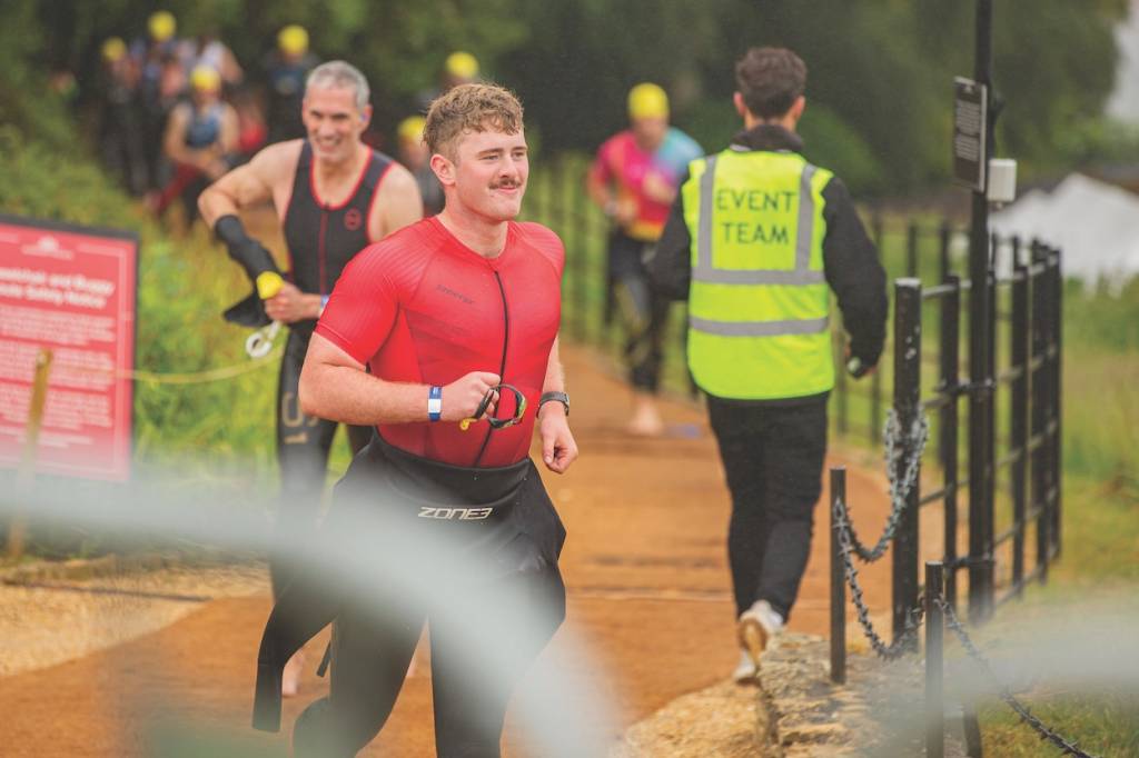A triathlete running with his wetsuit on